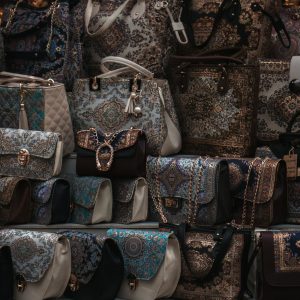 A close-up vertical shot showcasing various intricately designed handbags on display at a market stall.
