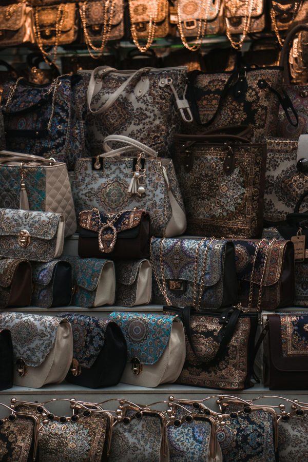 A close-up vertical shot showcasing various intricately designed handbags on display at a market stall.
