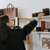 Woman browsing leather bags and wallets in a stylish retail shop.